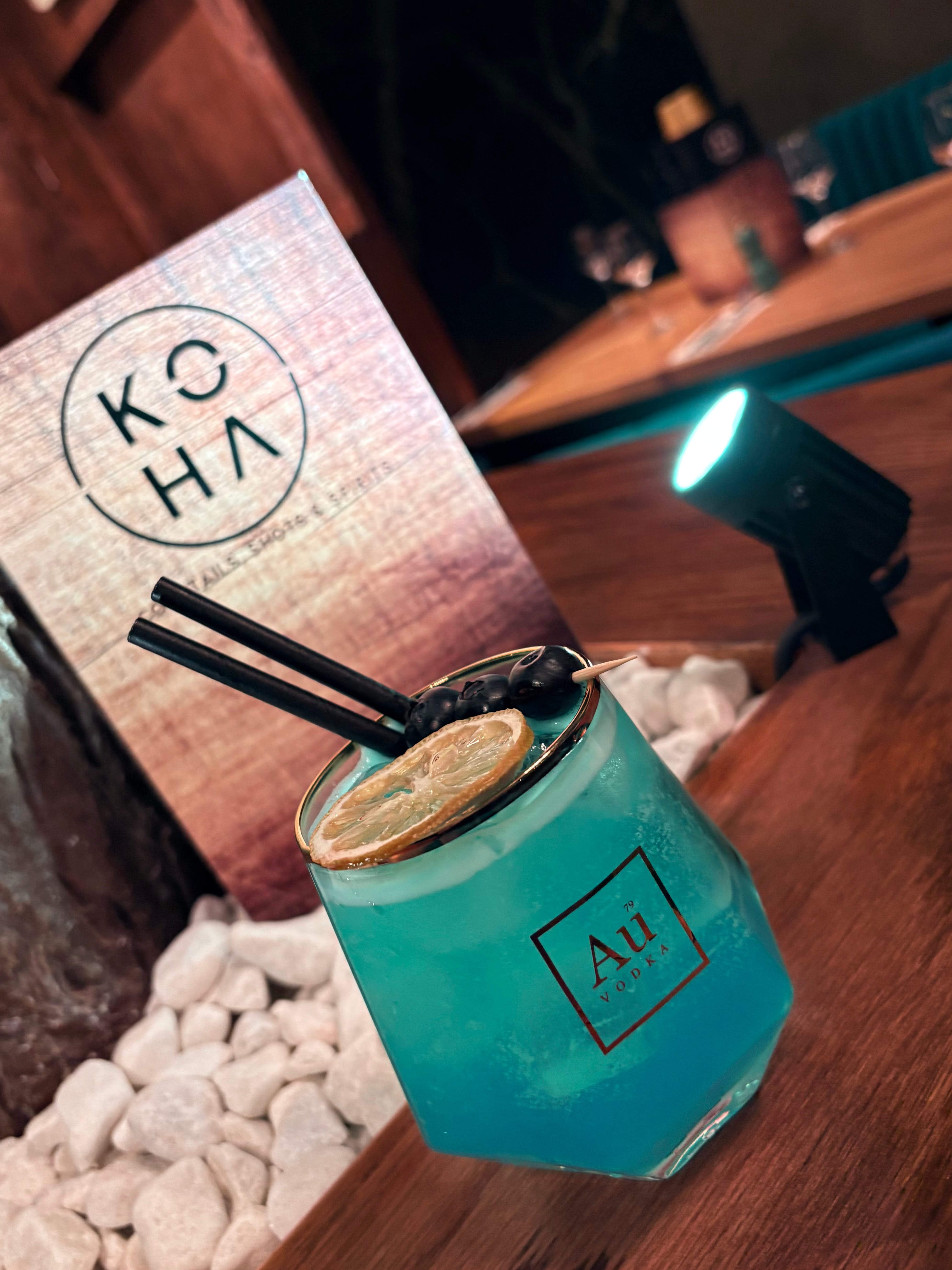 Blue lagoon cocktail in Au Vodka glass with lemon garnish