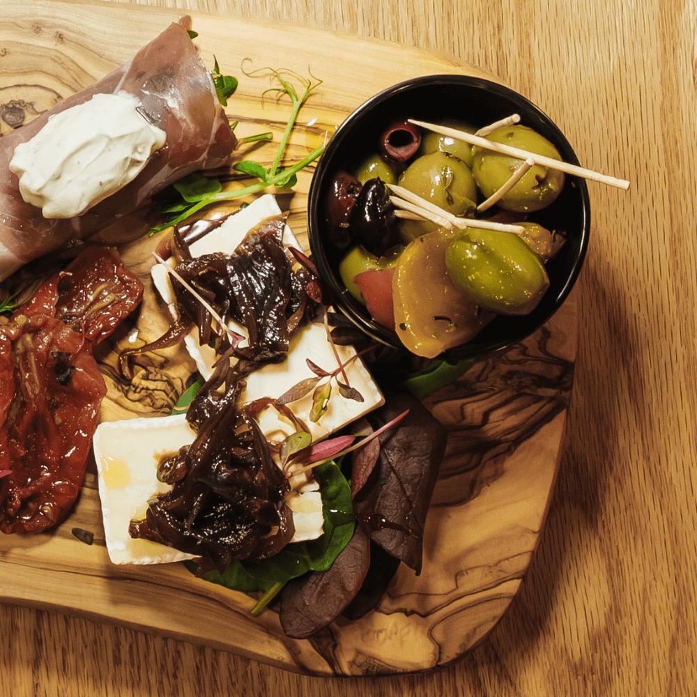 Antipasti board with prosciutto burrata, brie with caramelized onions, and olives